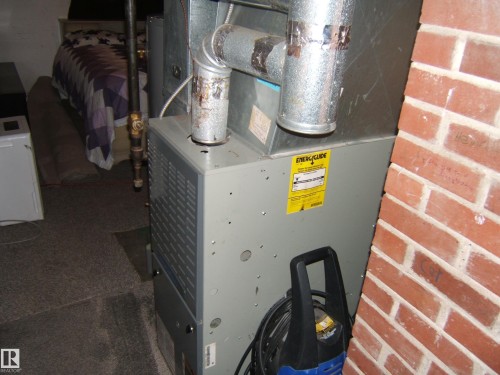 The property includes a utility area with an HVAC unit featuring an EnergyGuide label, situated on a carpeted floor - 5023 50 Street, Two Hills, AB - Indoor Photo Showing Basement
