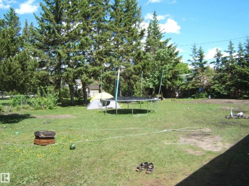 Expansive outdoor space featuring a fire pit and mature perimeter trees - 5023 50 Street, Two Hills, AB - Outdoor
