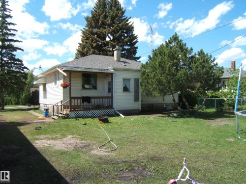 Rear exterior featuring white siding and a covered porch with lattice accents - 5023 50 Street, Two Hills, AB - Outdoor