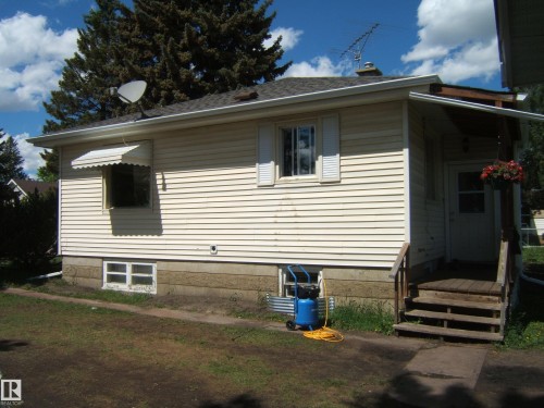 Exterior featuring horizontal siding, foundation with textured panels, and a wood-finish porch with stairs - 5023 50 Street, Two Hills, AB - Outdoor With Exterior