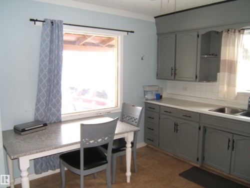 This kitchen features light blue walls, gray cabinetry, and a window providing natural light - 5023 50 Street, Two Hills, AB - Indoor Photo Showing Kitchen With Double Sink