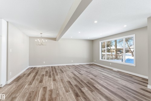 Spacious open concept living area featuring engineered hardwood flooring, recessed lighting, and a large window providing views of the surrounding outdoor area - 11 Sonora Drive, St. Albert, AB - Indoor Photo Showing Other Room