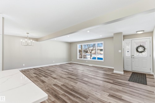 The property features wood-look flooring throughout, a front entry door with decorative glass inserts and sidelights, and a large window providing views of the outdoors - 11 Sonora Drive, St. Albert, AB - Indoor