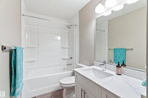 The bathroom features a modern vanity with a white countertop and an integrated sink, complemented by a large mirror and overhead lighting - 11 Sonora Drive, St. Albert, AB - Indoor Photo Showing Bathroom