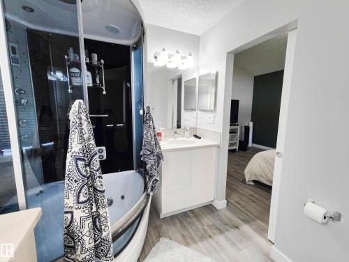 The bathroom features a standalone shower and tub combination, a vanity with a white countertop, and light-colored flooring - 215 Peter Close Nw, Edmonton, AB - Indoor Photo Showing Bathroom