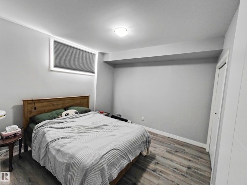 Bedroom featuring a window with blinds, light gray walls, a ceiling light fixture, and wood-look flooring - 215 Peter Close Nw, Edmonton, AB - Indoor Photo Showing Bedroom