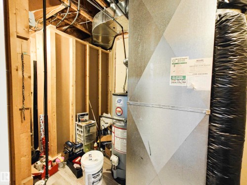 This utility area features exposed wooden framing, visible ductwork, and a water heater - 215 Peter Close Nw, Edmonton, AB - Indoor Photo Showing Basement