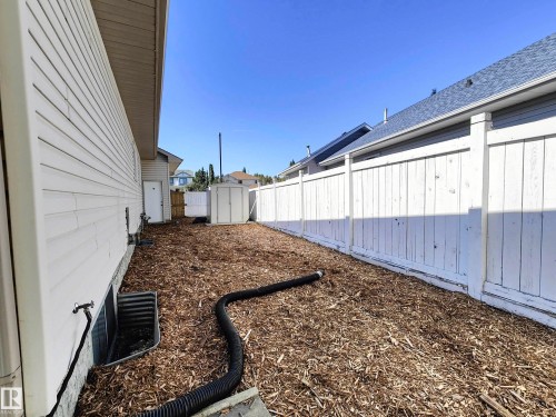 The property features white vinyl siding, a white privacy fence, and a storage shed - 215 Peter Close Nw, Edmonton, AB - Outdoor With Exterior