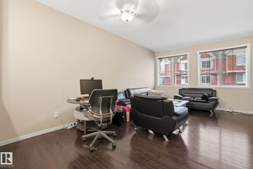Living area featuring dark hardwood floors, two windows with blinds, and a ceiling fan - 75 603 Watt Boulevard, Edmonton, AB - Indoor