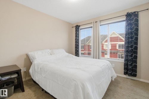 This bedroom features neutral-toned walls, carpet flooring, and windows with blinds - 75 603 Watt Boulevard, Edmonton, AB - Indoor Photo Showing Bedroom