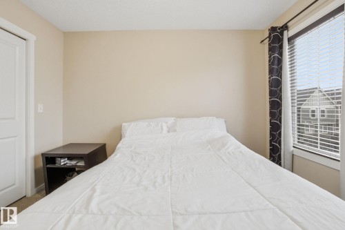 This room features neutral-toned walls, a white door, and a window with blinds and dark curtains - 75 603 Watt Boulevard, Edmonton, AB - Indoor Photo Showing Bedroom