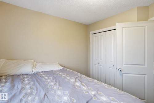 Room with light-colored walls and a textured ceiling, featuring a white bi-fold closet door and a white panel door - 75 603 Watt Boulevard, Edmonton, AB - Indoor Photo Showing Bedroom