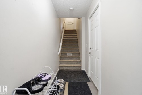 Entryway with light-colored walls, carpeted stairs, and a white paneled door - 75 603 Watt Boulevard, Edmonton, AB - Indoor Photo Showing Other Room