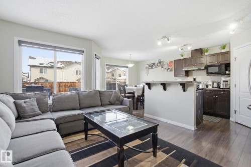 The main living area features durable wood flooring and large windows, providing abundant natural light - 3026 16A Avenue, Edmonton, AB - Indoor Photo Showing Living Room