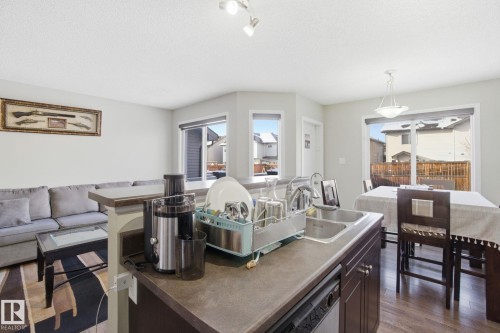 The property features an open concept kitchen and dining area, with a double basin sink, dark cabinetry, and a dishwasher - 3026 16A Avenue, Edmonton, AB - Indoor