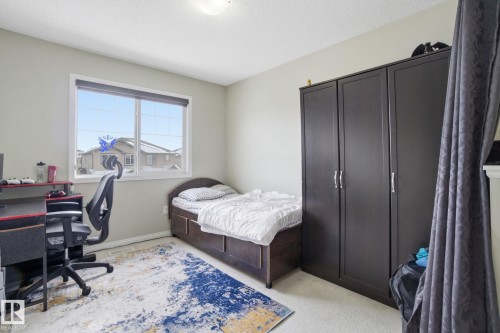 This room features light-colored walls and carpeting, a window with a view of residential structures, and a ceiling light fixture - 3026 16A Avenue, Edmonton, AB - Indoor Photo Showing Bedroom