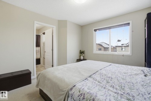This room features neutral-toned walls, a large window providing ample natural light, and carpeted flooring - 3026 16A Avenue, Edmonton, AB - Indoor Photo Showing Bedroom