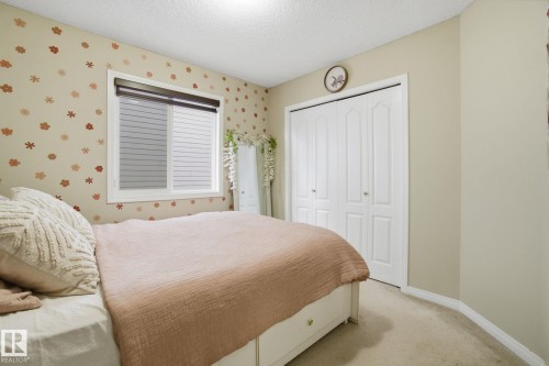 This bedroom features a window with blinds, carpet flooring, and a closet with bifold doors - 3026 16A Avenue, Edmonton, AB - Indoor Photo Showing Bedroom