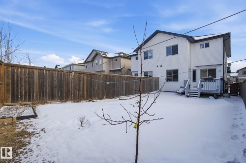 The property features a private backyard with a wooden fence and a two-story exterior with white siding and dark trim - 3026 16A Avenue, Edmonton, AB - Outdoor With Deck Patio Veranda