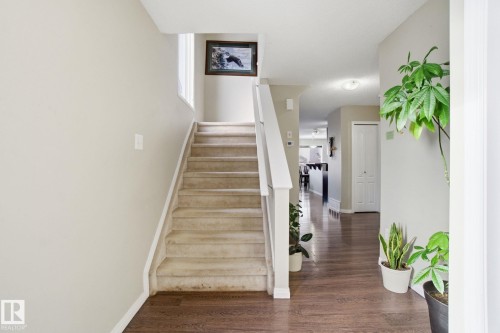 A spacious entryway featuring dark wood flooring, a carpeted staircase with white railings, and light-toned walls - 3026 16A Avenue, Edmonton, AB - Indoor Photo Showing Other Room