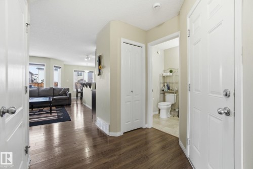 This inviting entry features rich wood flooring, a white paneled door, and a conveniently located powder room with a toilet - 3026 16A Avenue, Edmonton, AB - Indoor Photo Showing Other Room