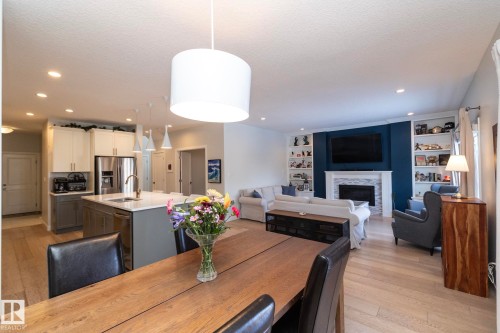 Open-concept living area featuring a kitchen with an island, a dining space, and a living room with built-in shelving and a fireplace - 26 Ellice Bend, Fort Saskatchewan, AB - Indoor With Fireplace