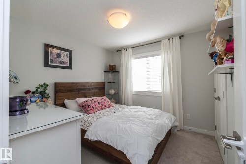 The property features a bedroom with light gray walls, a window with blinds and white curtains, and carpeted floors - 26 Ellice Bend, Fort Saskatchewan, AB - Indoor Photo Showing Bedroom