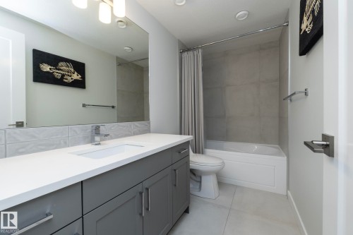 The bathroom features a vanity with a white countertop and gray cabinetry, a rectangular undermount sink, and a chrome faucet - 26 Ellice Bend, Fort Saskatchewan, AB - Indoor Photo Showing Bathroom