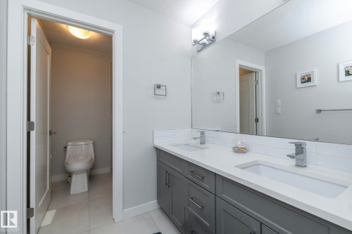 The bathroom features a double vanity with grey cabinetry, white countertops, and modern chrome fixtures - 26 Ellice Bend, Fort Saskatchewan, AB - Indoor Photo Showing Bathroom
