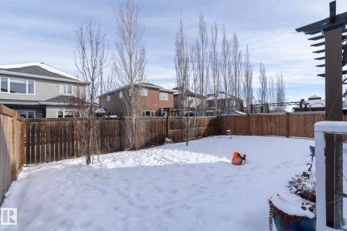 The property features a fenced yard covered in snow, with bare trees visible, and a pergola structure present - 26 Ellice Bend, Fort Saskatchewan, AB - Outdoor