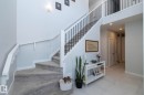 The property features a staircase with carpeted steps and a white railing, complemented by a white console table on a tiled floor - 26 Ellice Bend, Fort Saskatchewan, AB  - Indoor Photo Showing Other Room 
