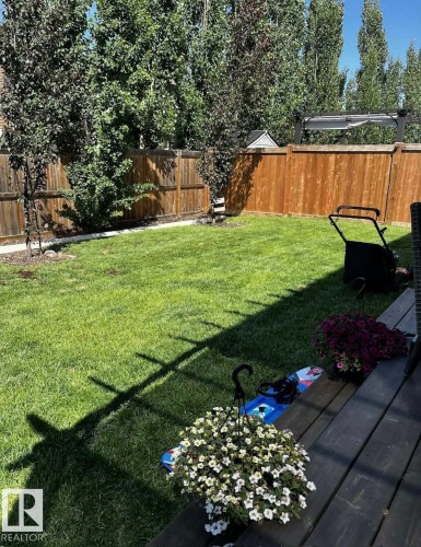 The property features a well-maintained yard with a manicured lawn and mature trees, enclosed by a wooden fence - 26 Ellice Bend, Fort Saskatchewan, AB - Outdoor