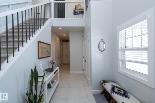 Inviting entryway featuring light-colored tile flooring, a window with blinds, and a staircase with white risers and black metal balusters - 26 Ellice Bend, Fort Saskatchewan, AB - Indoor Photo Showing Other Room