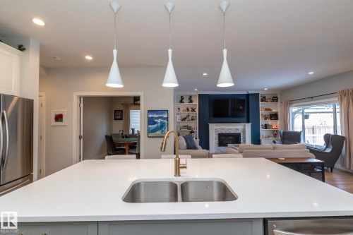 The kitchen features a large island with a stainless steel sink and a gold-toned faucet - 26 Ellice Bend, Fort Saskatchewan, AB - Indoor Photo Showing Kitchen With Fireplace With Double Sink