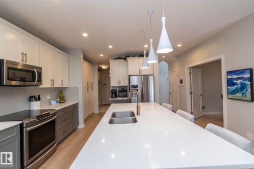 The kitchen features a large island with an integrated sink and pendant lighting - 26 Ellice Bend, Fort Saskatchewan, AB - Indoor Photo Showing Kitchen With Double Sink With Upgraded Kitchen