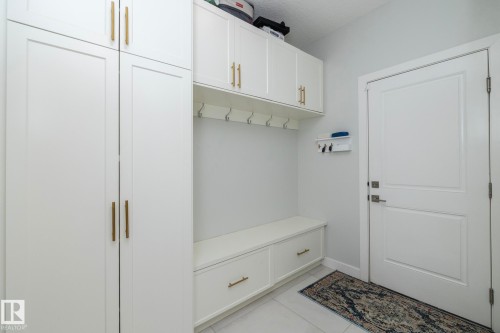 Entryway featuring white cabinetry with gold-toned hardware, a built-in bench with storage drawers, and wall-mounted hooks - 26 Ellice Bend, Fort Saskatchewan, AB - Indoor Photo Showing Other Room