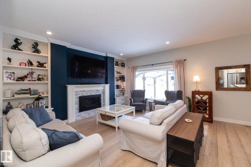 The living room features hardwood flooring, recessed lighting, and a fireplace with a light-toned tile surround and white mantel - 26 Ellice Bend, Fort Saskatchewan, AB - Indoor Photo Showing Living Room With Fireplace