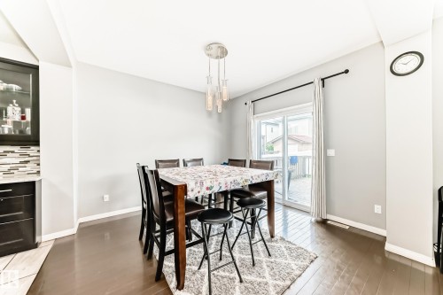 This dining area features hardwood floors and a sliding glass door providing access to the outdoors - 16720 61 Street, Edmonton, AB - Indoor Photo Showing Dining Room