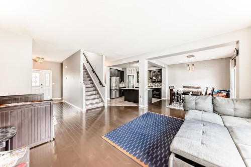 This property features an open-concept living area with hardwood flooring, a staircase with carpeted treads, and a dining area - 16720 61 Street, Edmonton, AB - Indoor