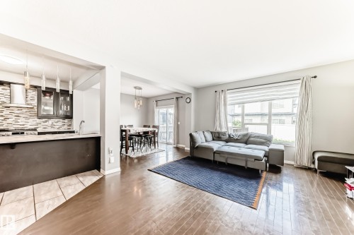 Open concept living space featuring hardwood floors, a kitchen with a tiled backsplash, and a dining area with a sliding glass door - 16720 61 Street, Edmonton, AB - Indoor Photo Showing Living Room
