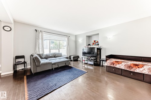The spacious living area features hardwood floors, light gray walls, and a large window with blinds and curtains - 16720 61 Street, Edmonton, AB - Indoor Photo Showing Living Room