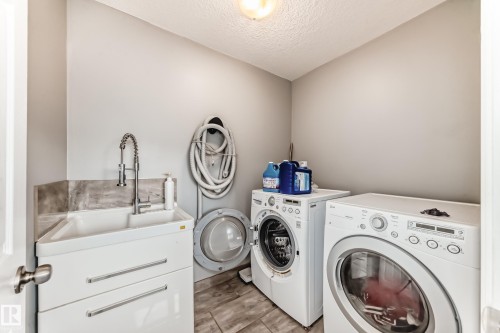 The laundry room features a utility sink with a pull-down faucet, a washing machine, and a dryer - 16720 61 Street, Edmonton, AB - Indoor Photo Showing Laundry Room
