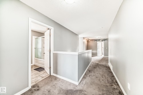 The property features gray carpeting throughout the hallway, with light gray painted walls and white trim - 16720 61 Street, Edmonton, AB - Indoor Photo Showing Other Room