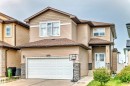 The property features a two-story exterior with beige siding and stone accents, a two-car garage, and a covered front entrance - 16720 61 Street, Edmonton, AB  - Outdoor With Facade 