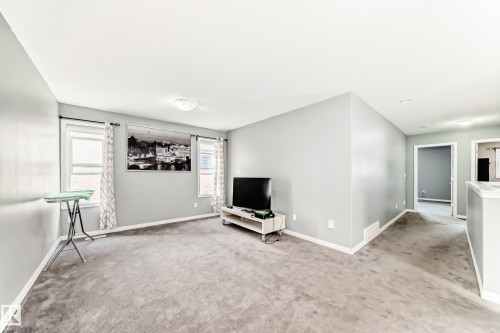 The property features a spacious room with light gray walls, gray carpet, and two windows providing natural light - 16720 61 Street, Edmonton, AB - Indoor