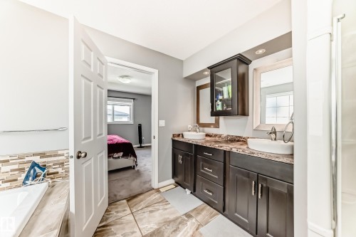 Bathroom with a double vanity featuring vessel sinks, dark wood cabinetry, and a countertop with visible veining - 16720 61 Street, Edmonton, AB - Indoor Photo Showing Bathroom