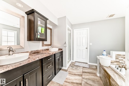 Bathroom featuring a dual vanity with vessel sinks, dark wood cabinetry, and a textured countertop - 16720 61 Street, Edmonton, AB - Indoor Photo Showing Bathroom