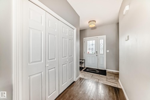 The entryway features a front door with decorative glass inserts, a ceiling light fixture, and a combination of wood-look and tiled flooring - 16720 61 Street, Edmonton, AB - Indoor Photo Showing Other Room