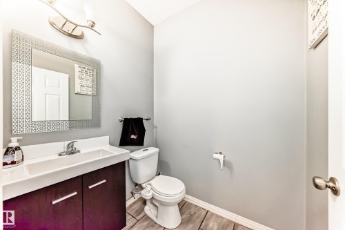 The bathroom features a vanity with a white countertop and a rectangular sink, a toilet, and light-toned flooring - 16720 61 Street, Edmonton, AB - Indoor Photo Showing Bathroom