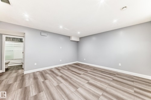 This property offers an open area with light grey walls, recessed lighting, and wood-look flooring - 16720 61 Street, Edmonton, AB - Indoor